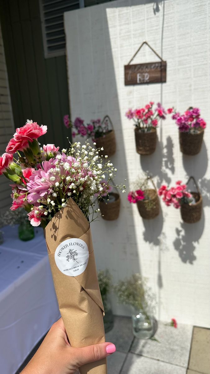 a person holding a brown paper bag with pink and white flowers in it on a table