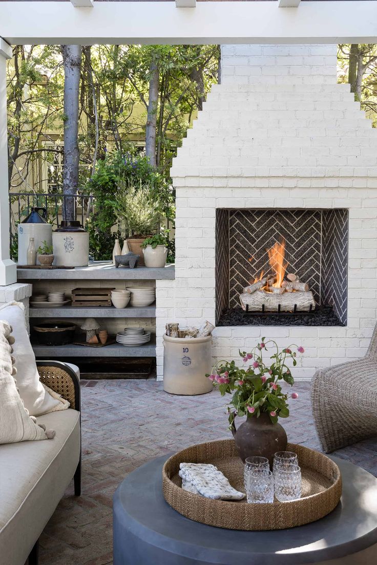 a living room filled with furniture and a fire place in the middle of a patio