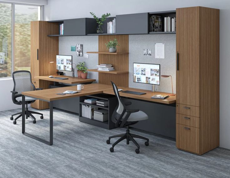 an office cubicle with two desks, chairs and shelves on the wall next to it