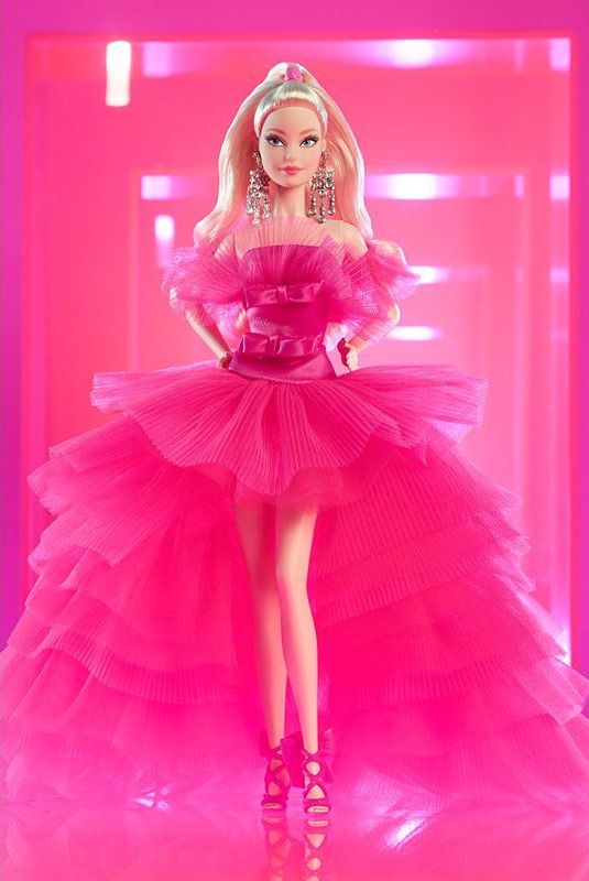 a barbie doll wearing a pink dress and high heeled sandals in front of a bright pink background