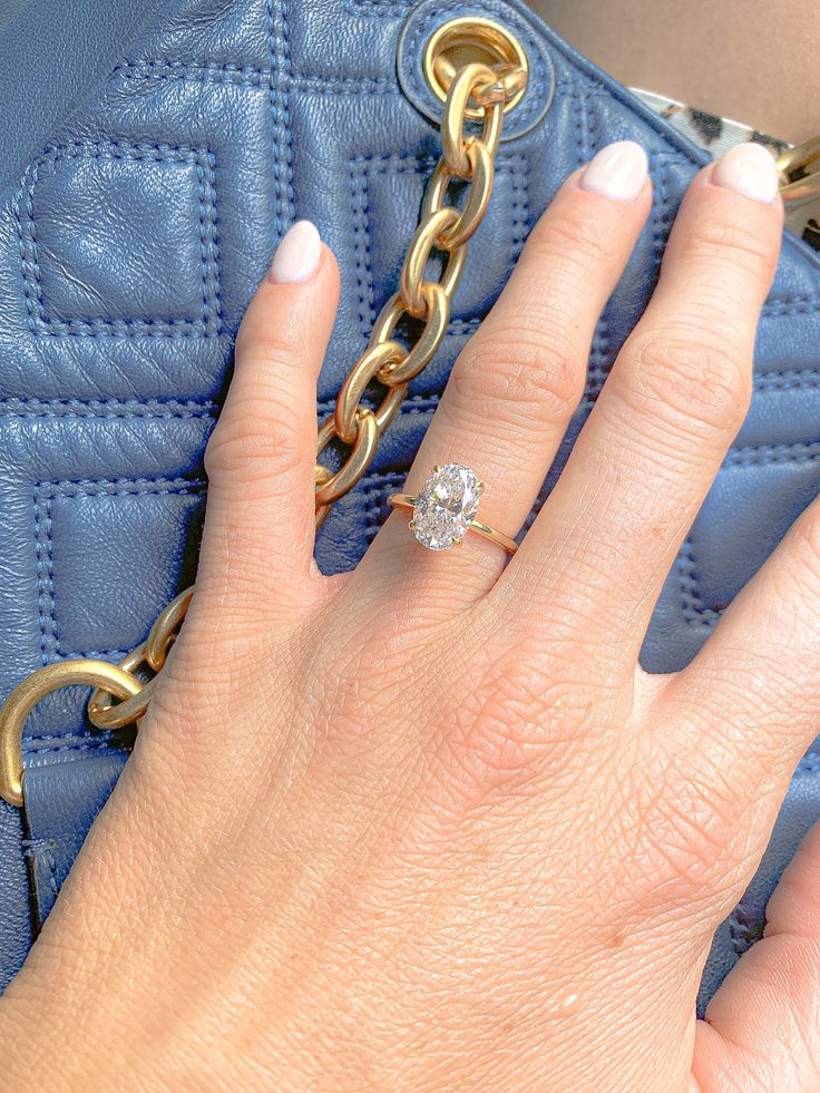 a woman's hand holding onto a blue purse with a gold chain around it