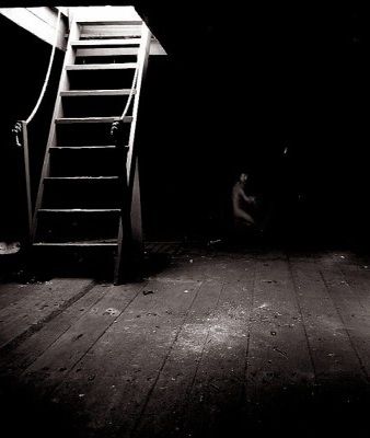 a ladder leaning up against a wall in the dark with a person sitting on it