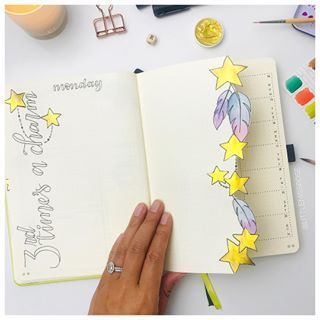 someone is writing in a notebook with stars on the page and other items surrounding it