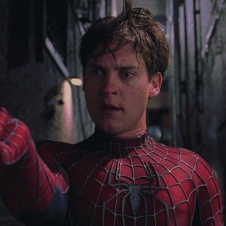 the amazing spider - man from the movie is pointing at something in his hand while wearing a red and black suit