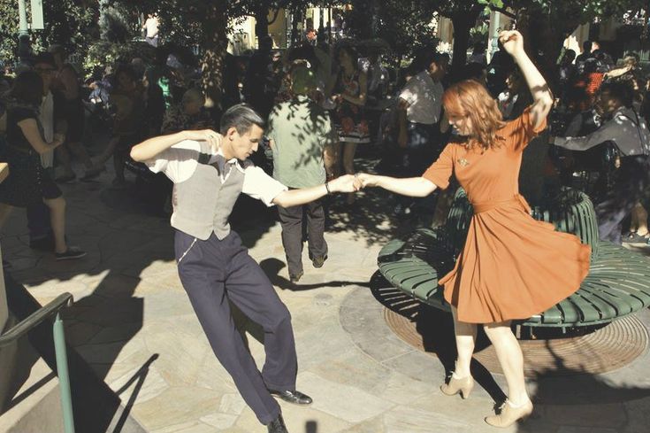 a man and woman dancing in front of a group of people at an outdoor event