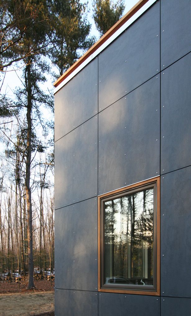 the side of a building with two windows and no roof is shown in front of some trees