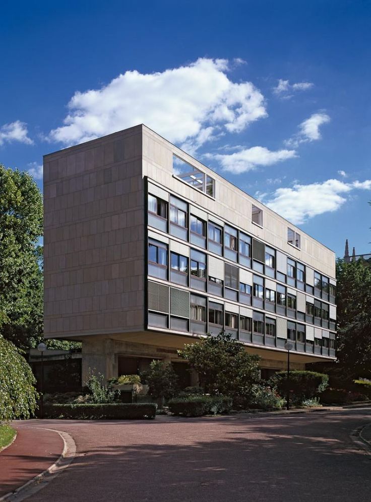 a large building with lots of windows on the side of it's face in front of some trees and bushes