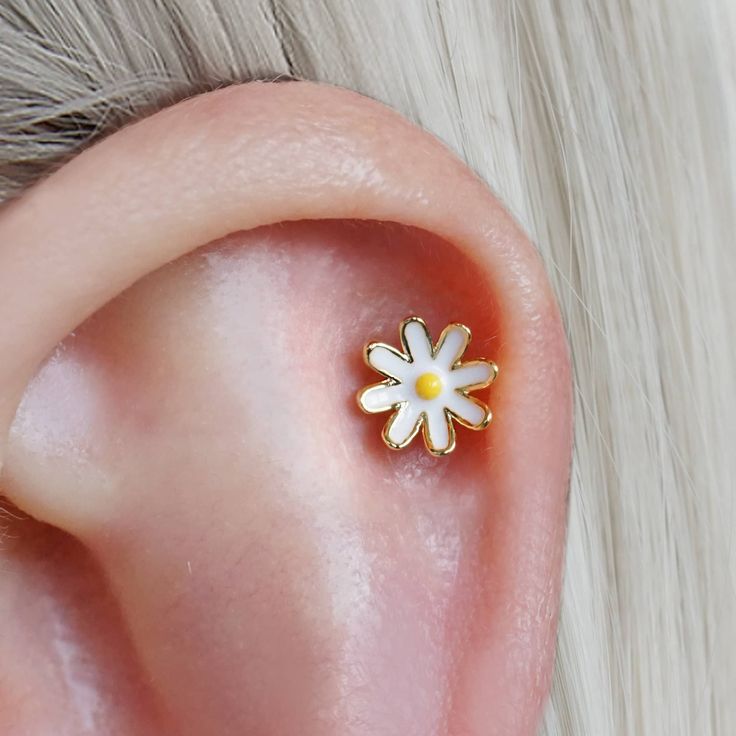 a close up of a person's ear with a small flower on the side