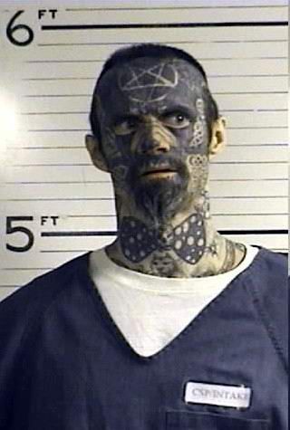 a man with tattoos on his face and neck is mugged in front of a mug