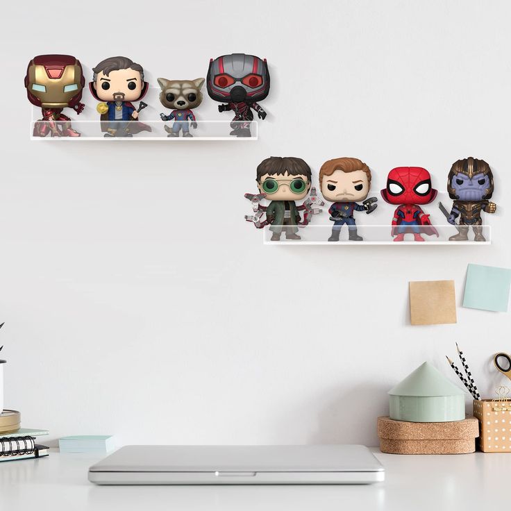 three shelves filled with action figures on top of a white desk next to a laptop