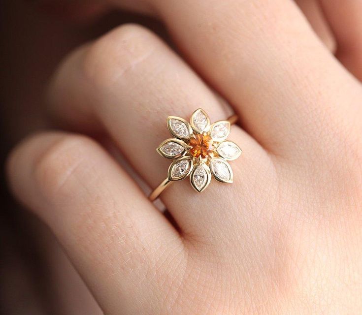 a close up of a person's hand wearing a ring with flowers on it