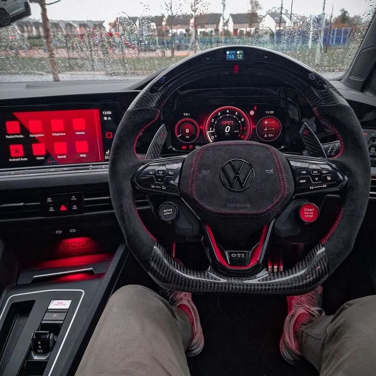 the interior of a car with red and black dash lights, steering wheel controls and dashboard gauges