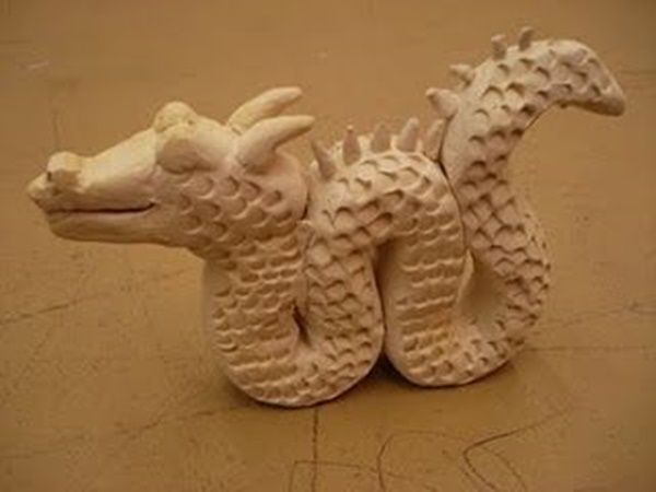 a white dragon figurine sitting on top of a brown floor next to a wall