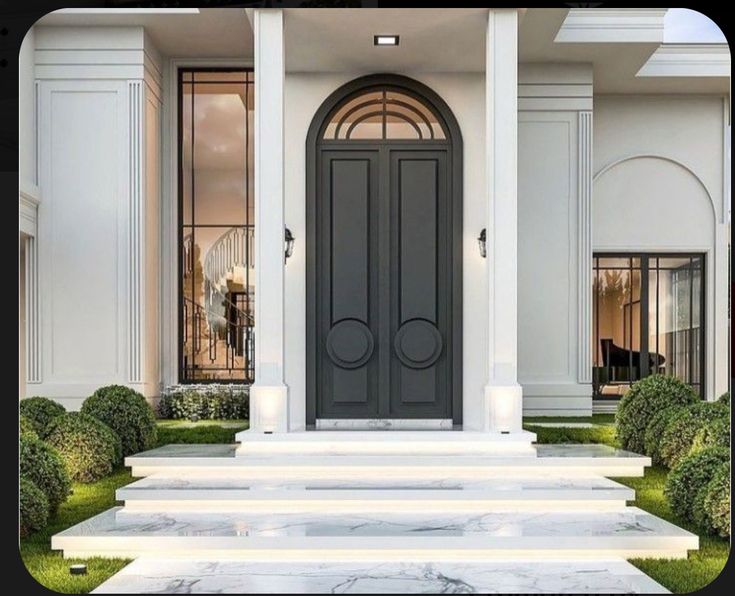 the front entrance to a luxury home with steps leading up to it and bushes on either side