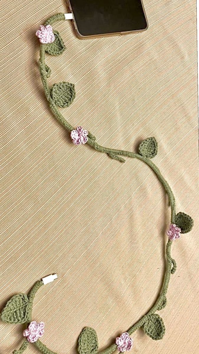 a cell phone is hooked up to a crocheted cord with flowers on it