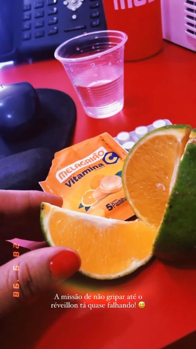 an orange cut in half sitting on top of a red table next to a cup