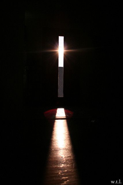 the light shines brightly through an opening in a dark room with a cross on it