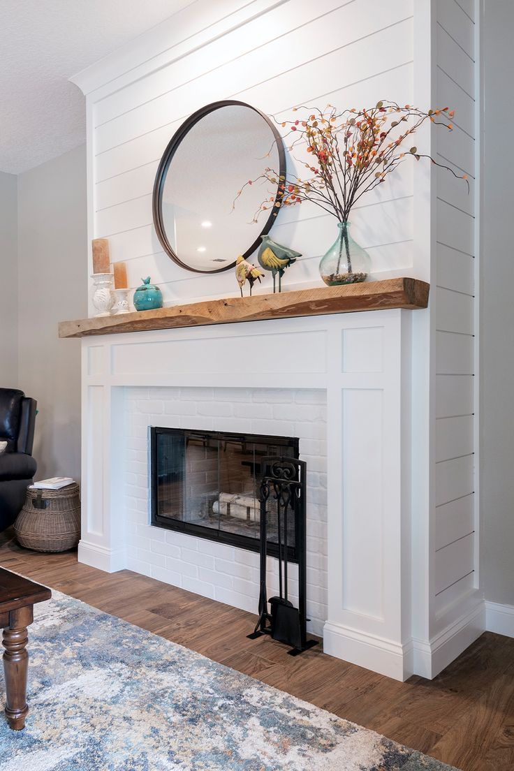 A white shiplap fireplace with warm wood accents. Styled with a round metal mirror, candles, and faux fall stems. Beach Home Fireplace, Coastal Fireplace Ideas Beach, Shiplap Fireplace Wall With Wood Mantle, Beach Cottage Fireplace, Coastal Electric Fireplace Ideas, Coastal Fireplace Makeover, Stained Shiplap Fireplace, Tile And Shiplap Fireplace, Shiplap Over Brick Fireplace