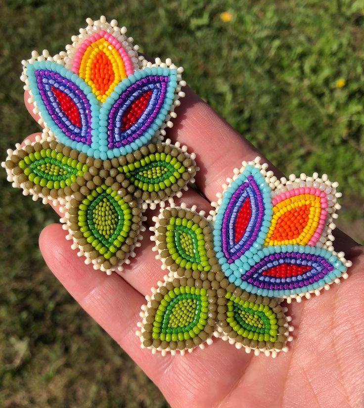 two colorful beaded earrings sitting on top of a person's hand