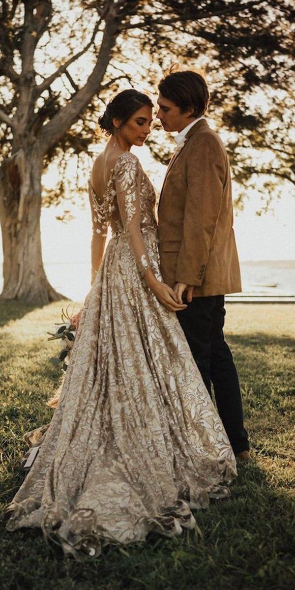 a man and woman standing next to each other in front of some trees on the grass