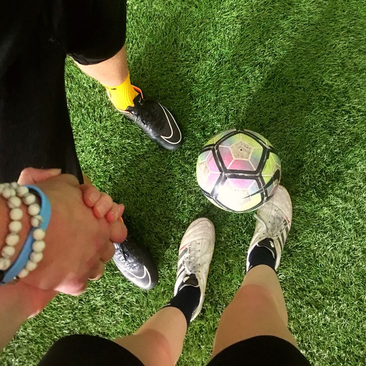 two people holding hands and standing next to a soccer ball