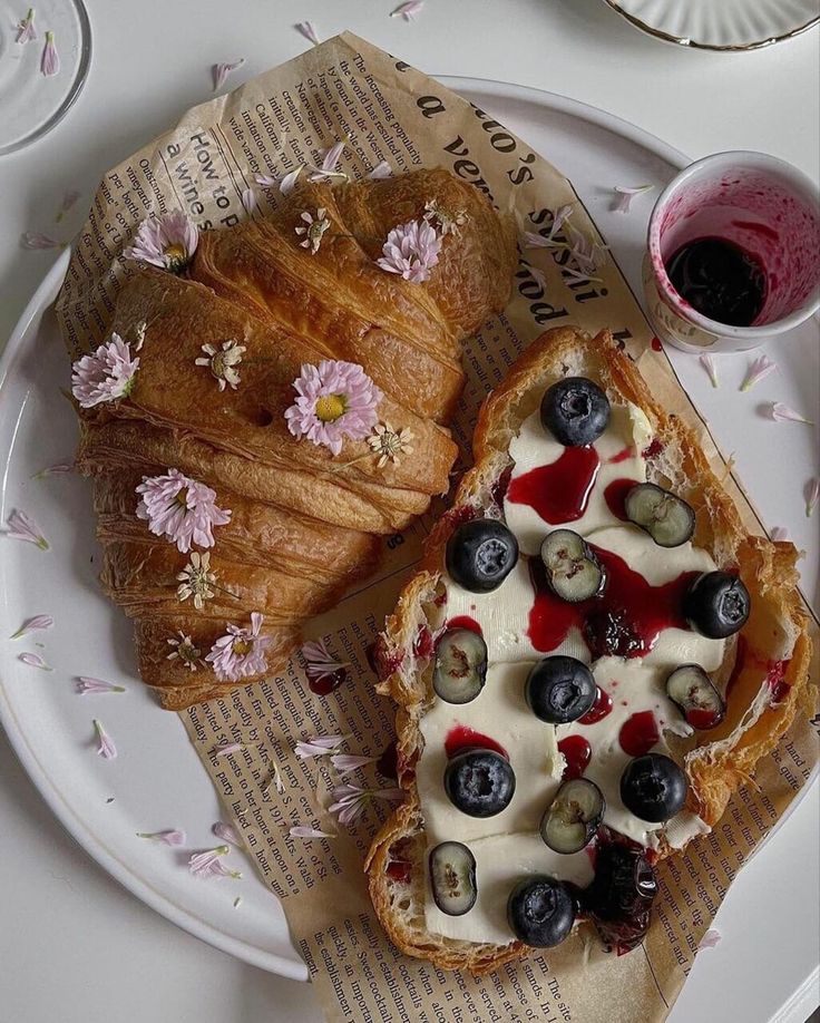 two croissants with blueberries, cream cheese and berries on them are sitting on a paper plate