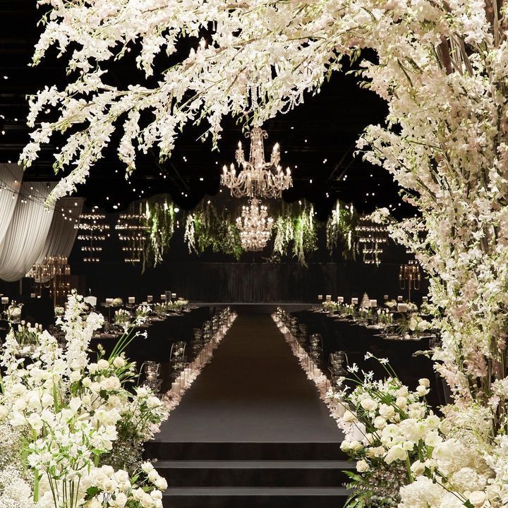 an outdoor wedding ceremony with white flowers and chandelier in the background at night