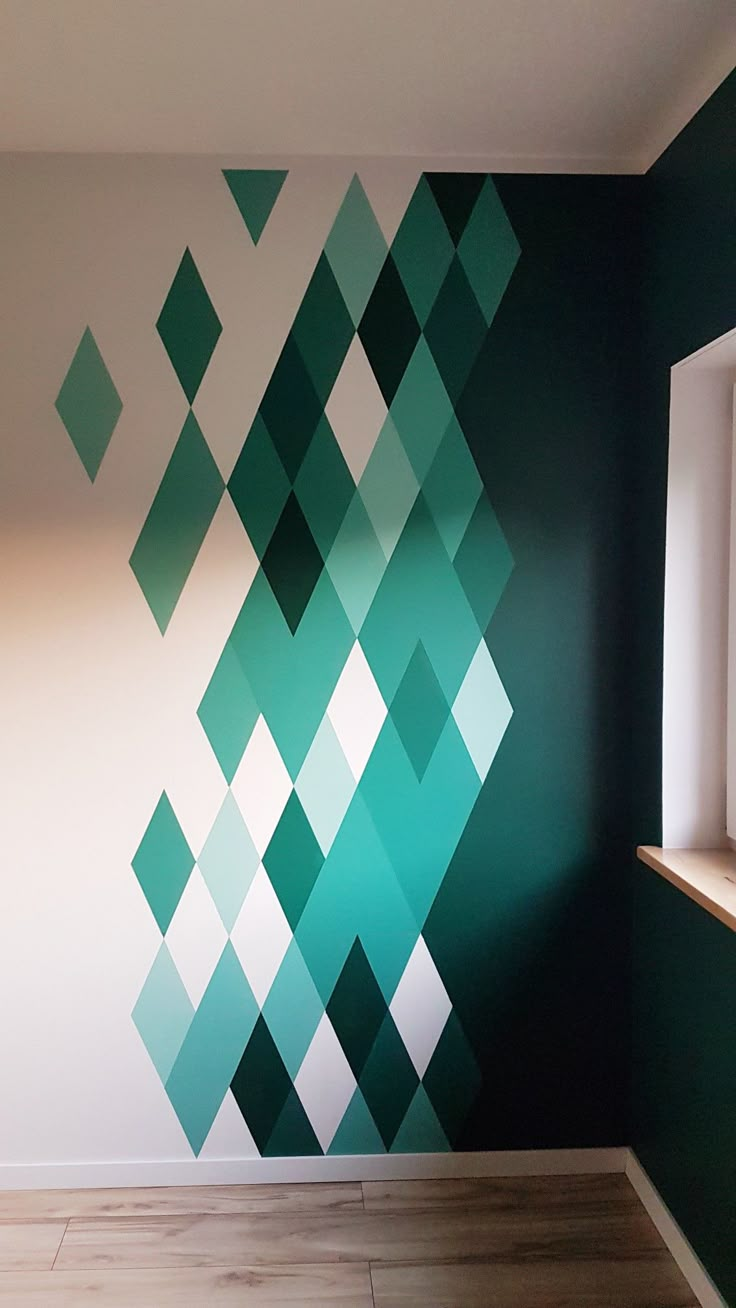 an empty room with green and white squares painted on the wall next to a window