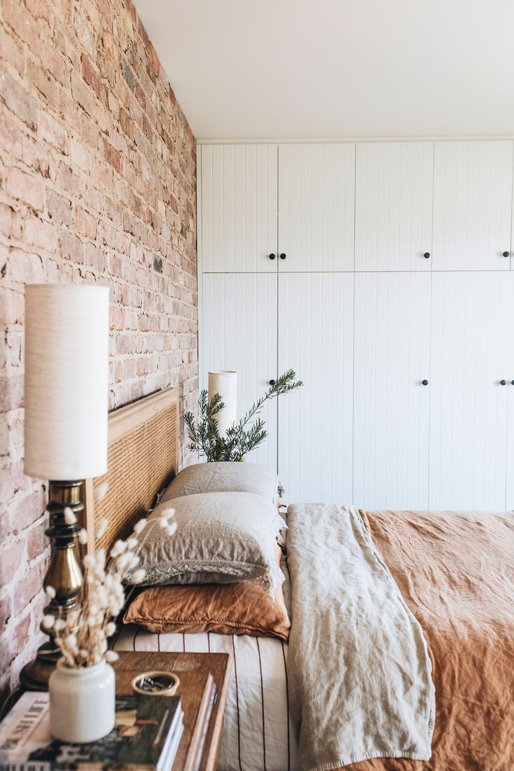 a bed sitting next to a brick wall in a bedroom