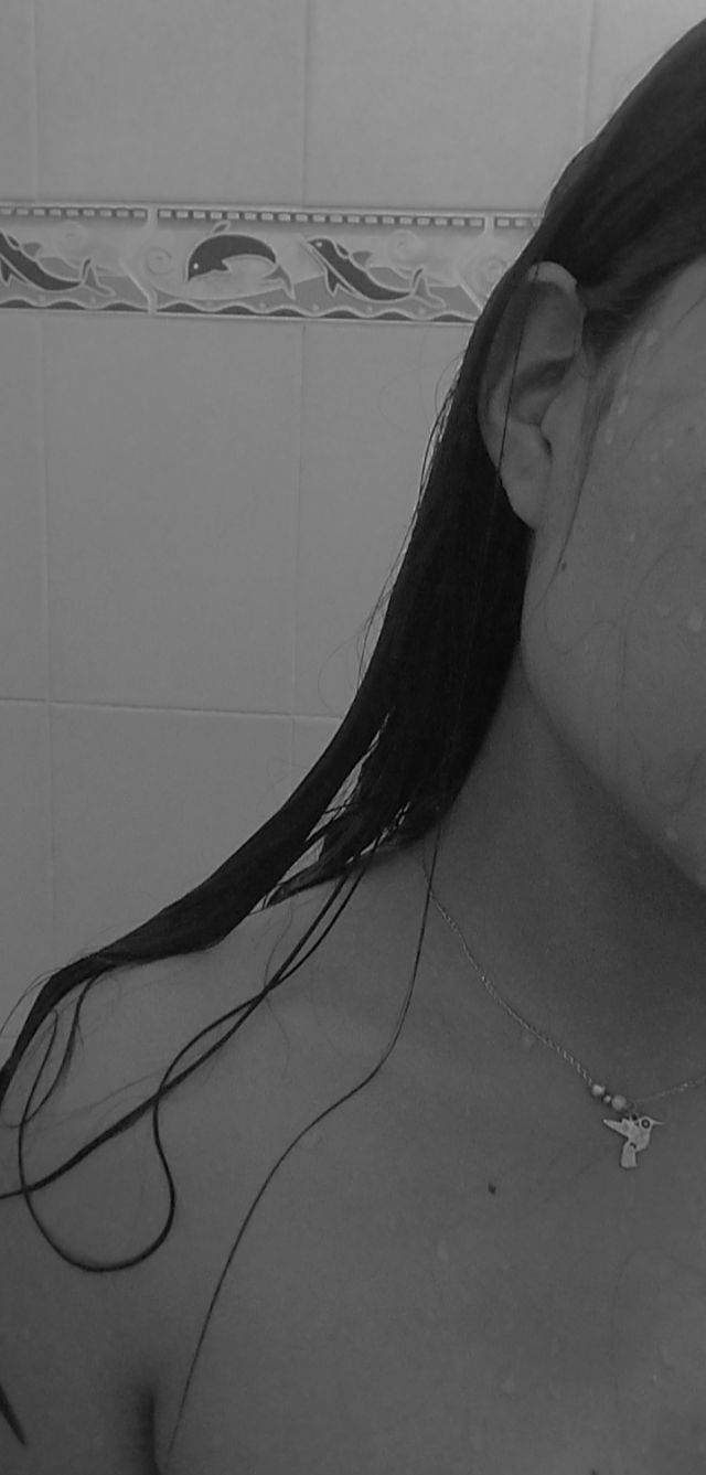 black and white photograph of a woman in the bathroom brushing her teeth with an electric toothbrush