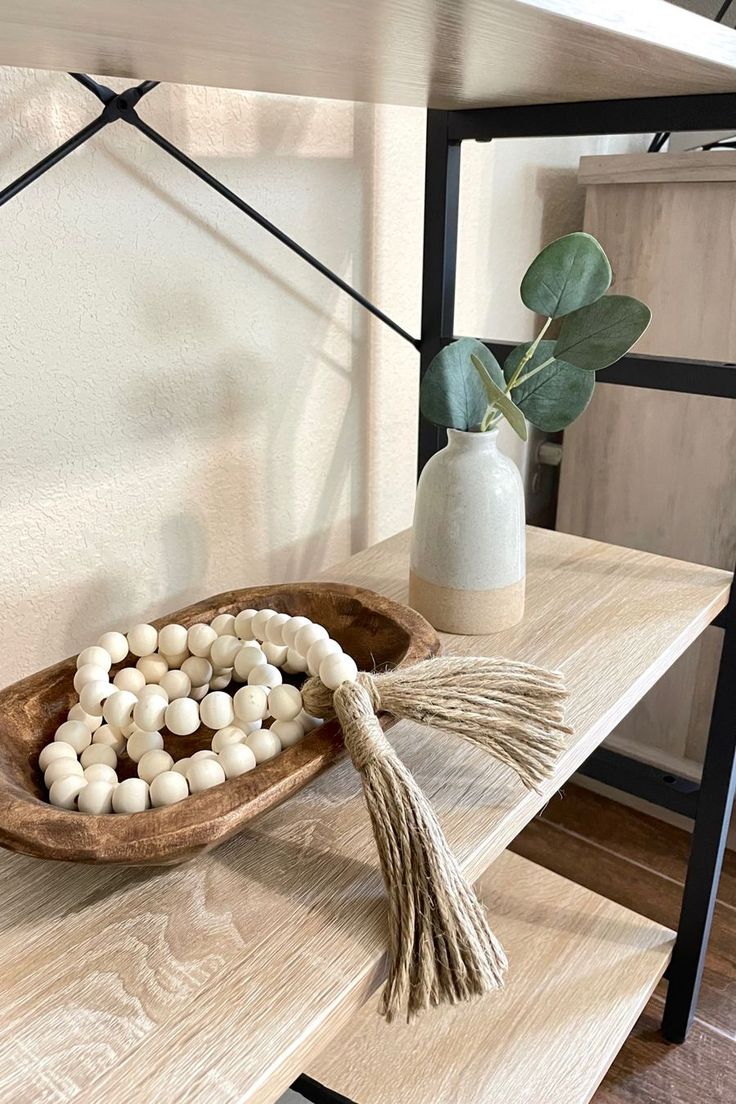 a wooden bowl filled with white balls and tassels on top of a table