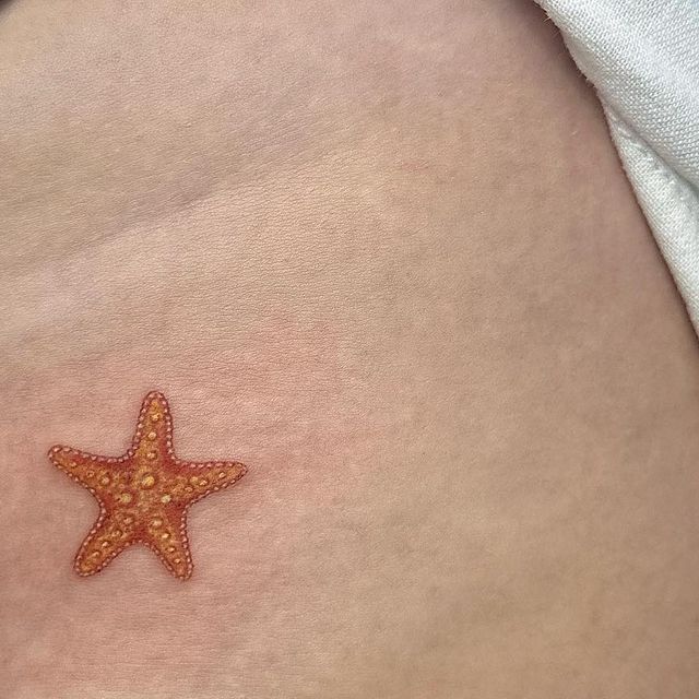 an orange starfish on the side of a woman's stomach with small dots