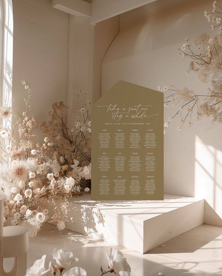 a wedding seating plan is displayed on a table with flowers in front of the window