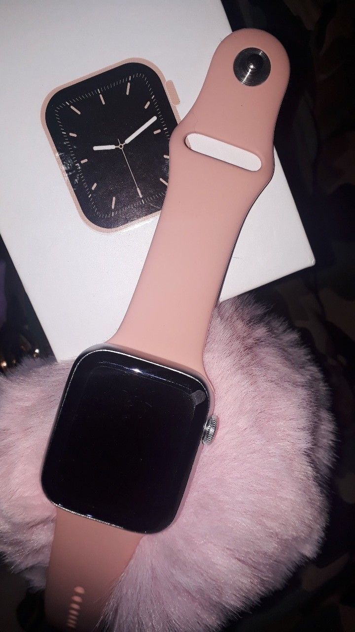 an apple watch is sitting on top of a pink fur ball next to a white box