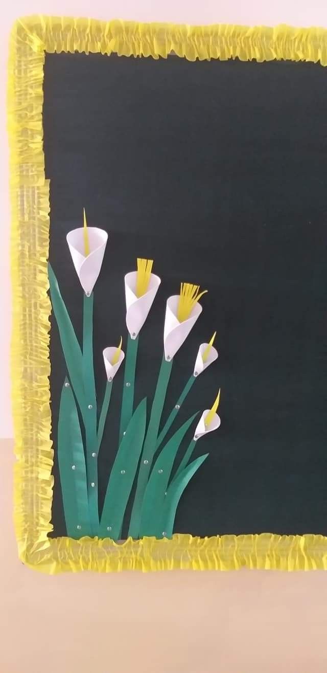 some white flowers are in front of a black board with yellow trim on the edges