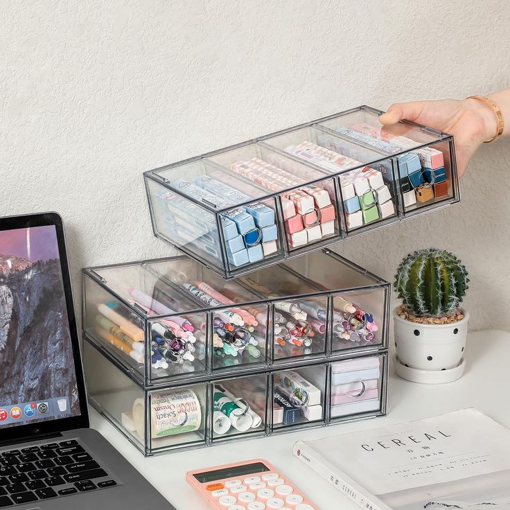 a laptop computer sitting on top of a desk next to a clear container filled with pens and pencils