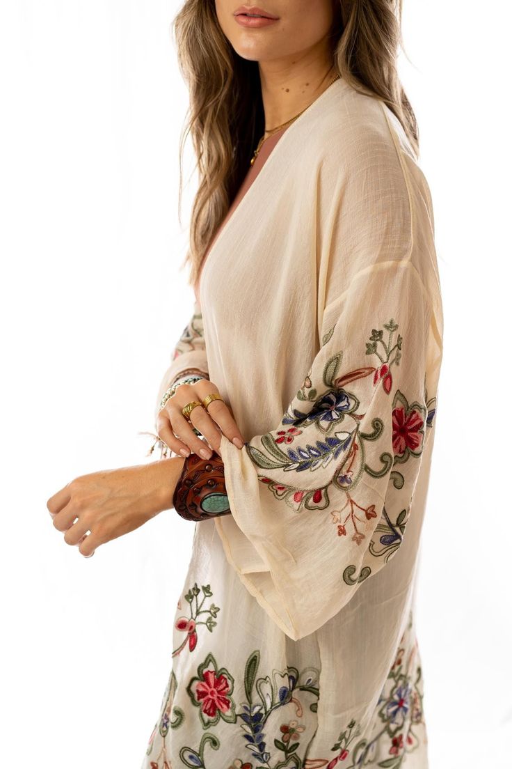 Nothing is more fun than a kimono covered in floral! This perfect layering piece features a sheer fabric in a longline silhouette with accents of crochet florals in multicolors along the hem and wide sleeves.Model is 5'8" and wearing one size.100% Polyester, Imported. OS sizing fits most* sizes US 0-18Length: 38 inBust Across: 25 inSleeve Length: 17 inSleeve Opening: 11 in Bohemian Sheer V-neck Cover-up, Embroidered V-neck Kimono For Spring, Beige Floral Print Beach Kimono, Beige Flowy Bohemian Kimono, Flowy Bohemian Beige Kimono, Spring Sheer Long Sleeve Kimono, Long Sleeve Summer Layering Cover-up, Hippie Long Kimono For Spring, Long Hippie Kimono For Spring