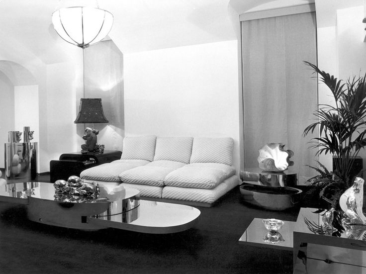 a black and white photo of a living room with couches, coffee table, lamps and other furniture