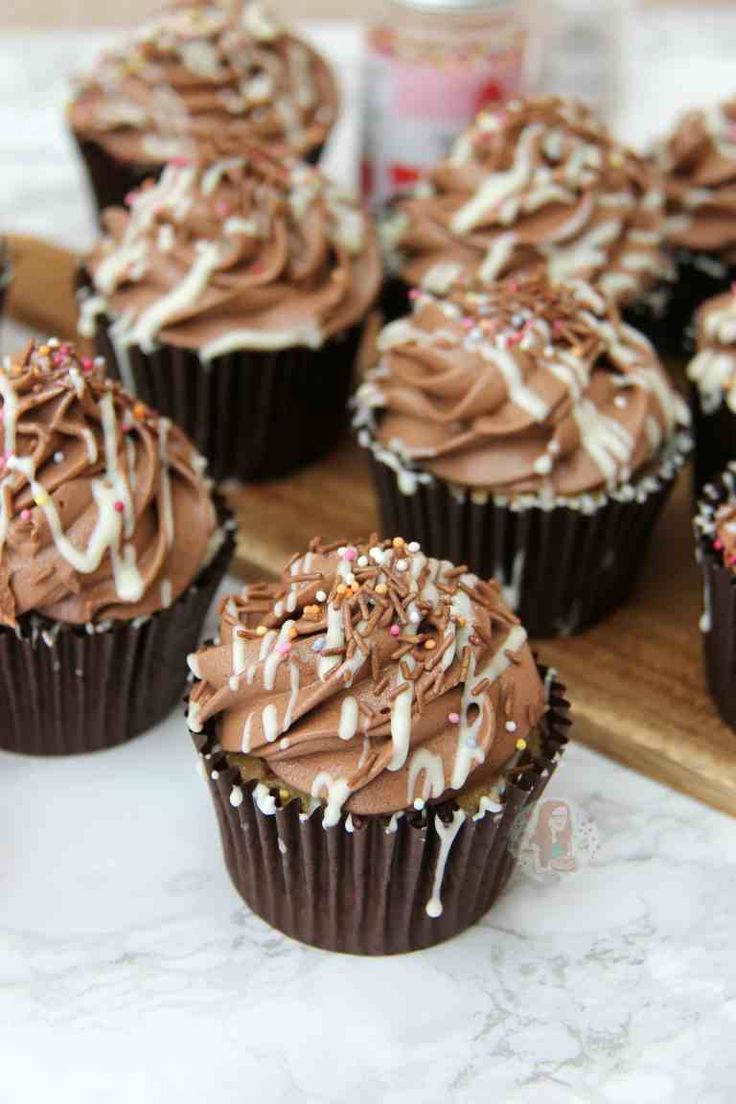 chocolate cupcakes with frosting and sprinkles on a wooden tray