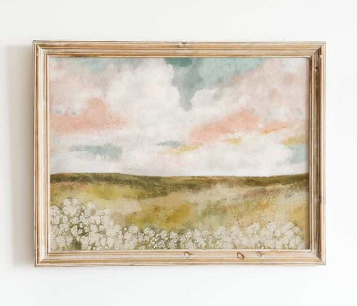 a painting hanging on the wall above a bed of white and pink flowers in front of a cloudy sky