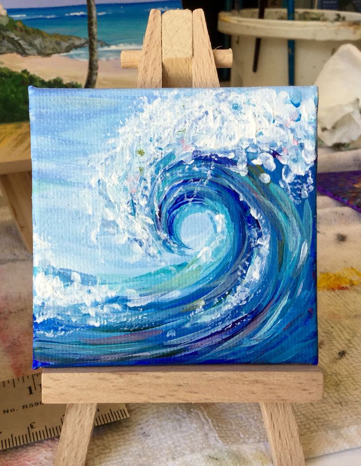 an easel with a painting on it that has a blue wave coming out of the water