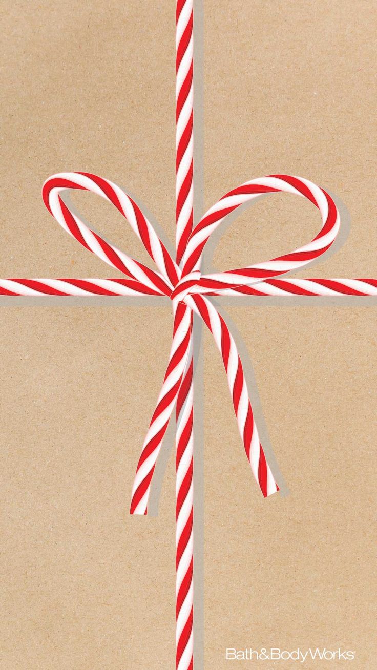 a red and white striped candy cane tied to a brown wrapping paper with a bow on it