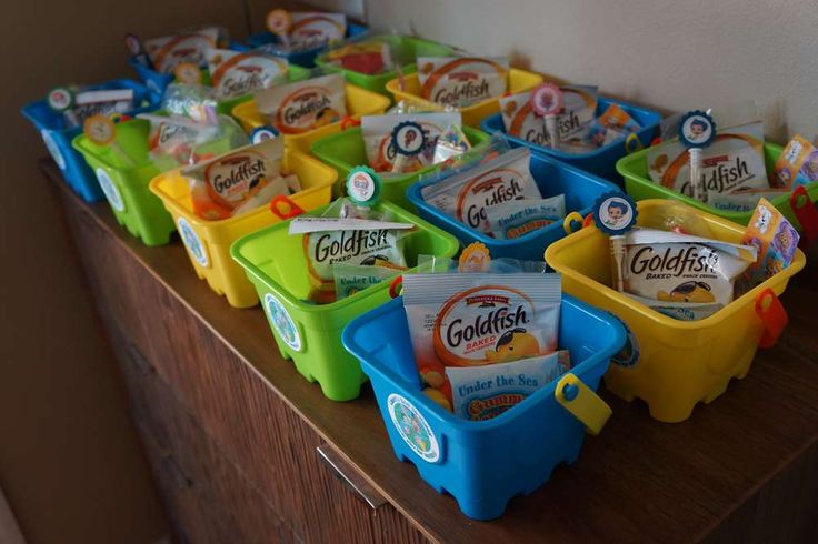 several plastic containers filled with snacks sitting on top of a wooden table next to a wall