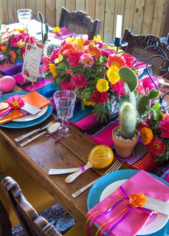 the table is set with colorful flowers and place settings