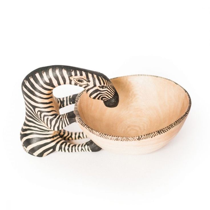 a wooden bowl with two zebras on the side and one in the middle, sitting next to it