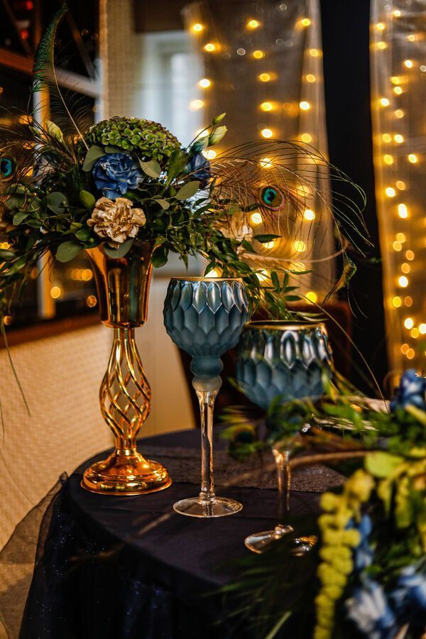 two wine glasses sitting on top of a table next to a vase filled with flowers