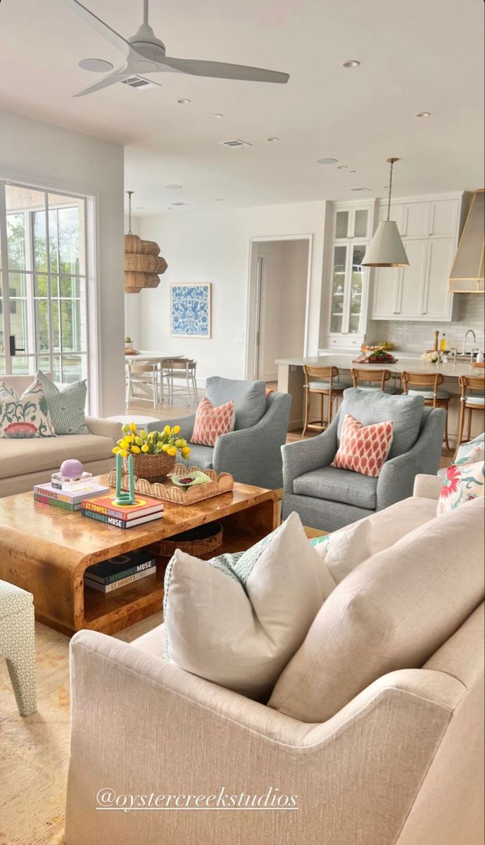 a living room filled with furniture and a ceiling fan in the middle of an open floor plan