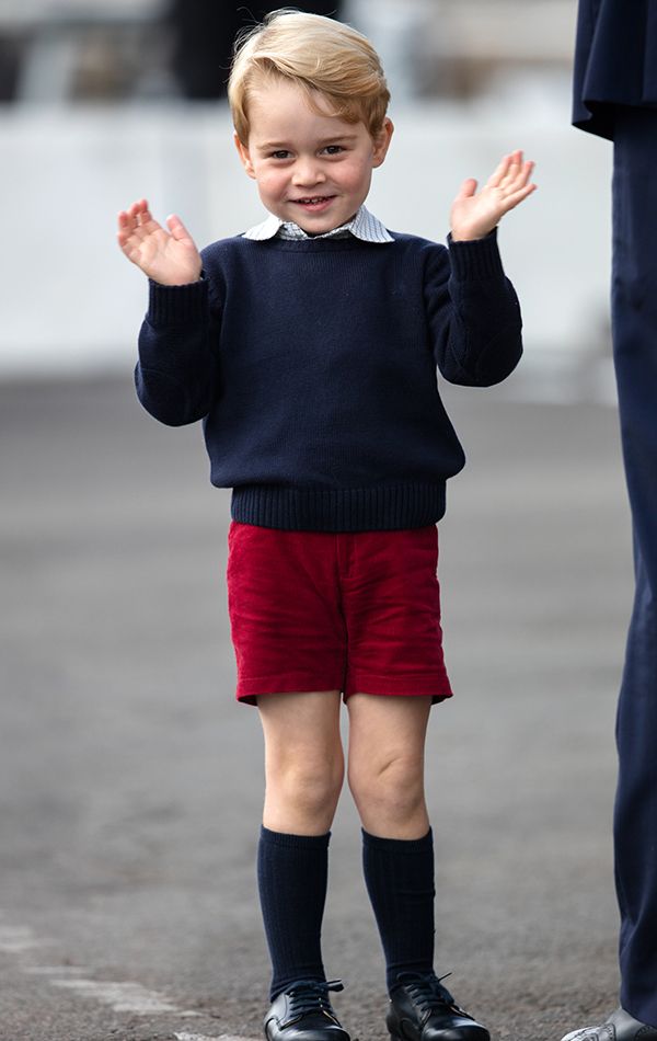 the young boy is wearing red shorts and a blue sweater