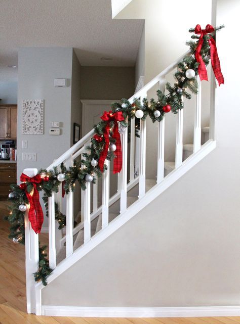 a christmas garland on the banisters of a house with red and white bows