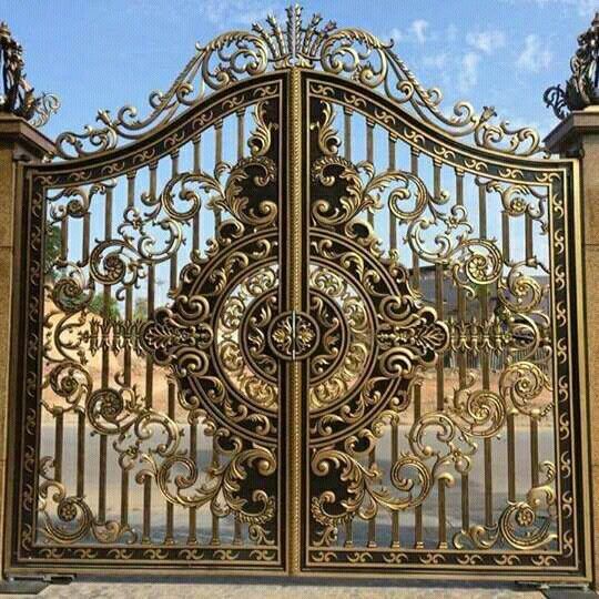 an ornate iron gate is shown in front of a blue and white sky with clouds